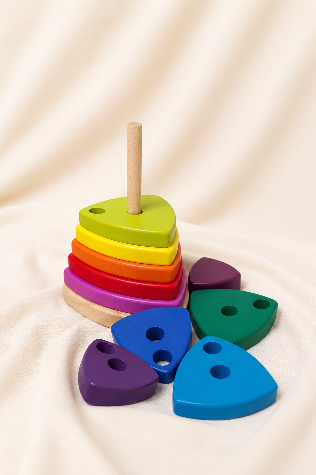 Colorful wooden stacking toy with heart-shaped pieces on a beige fabric background
