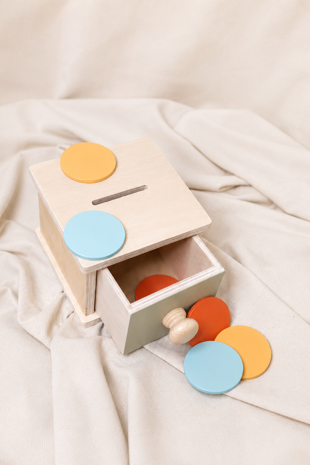 Wooden toy with colorful coins on a soft beige fabric background
