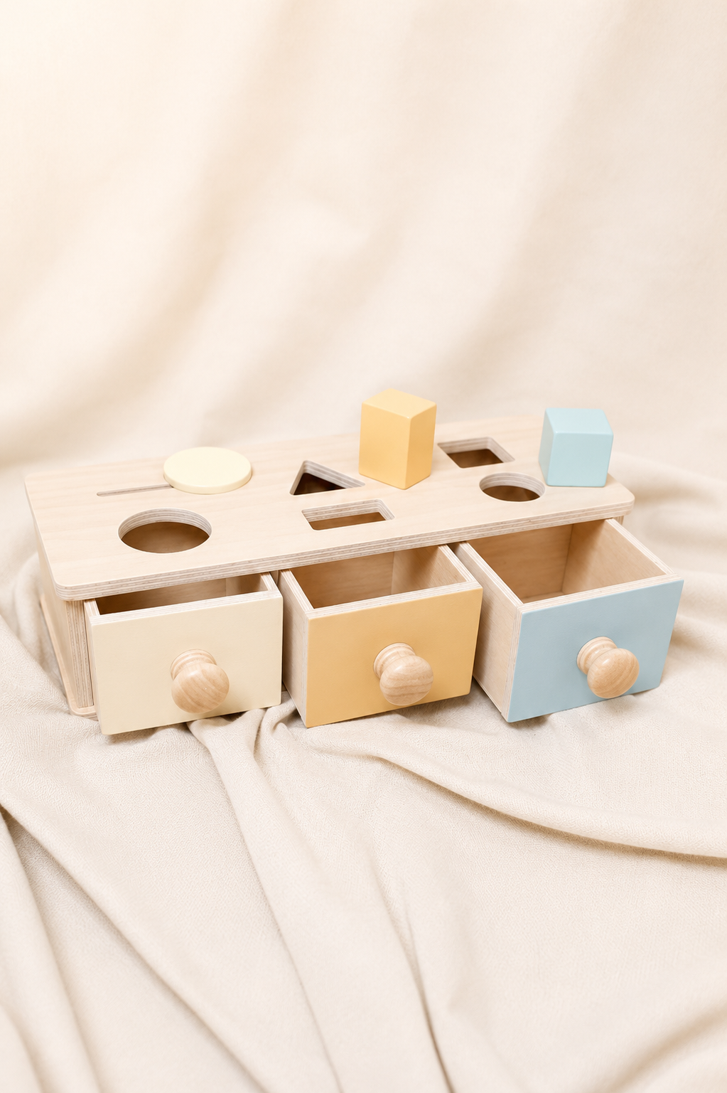 Wooden toy with multiple drawers and geometric blocks on a beige background