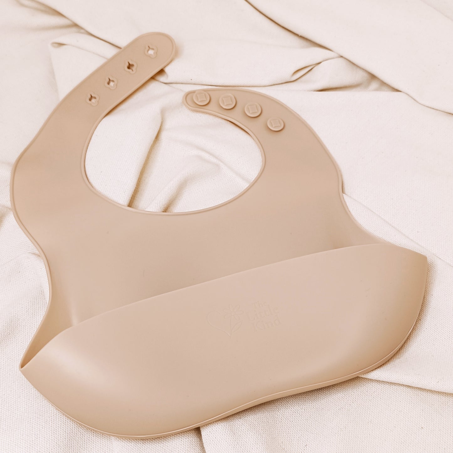 Beige baby bib on a white fabric background