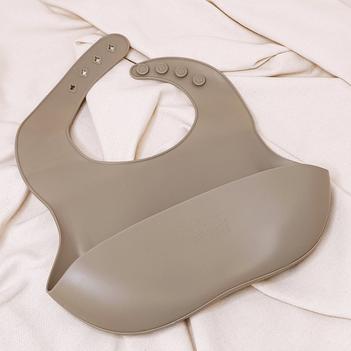 Olive silicone bib on a white fabric background