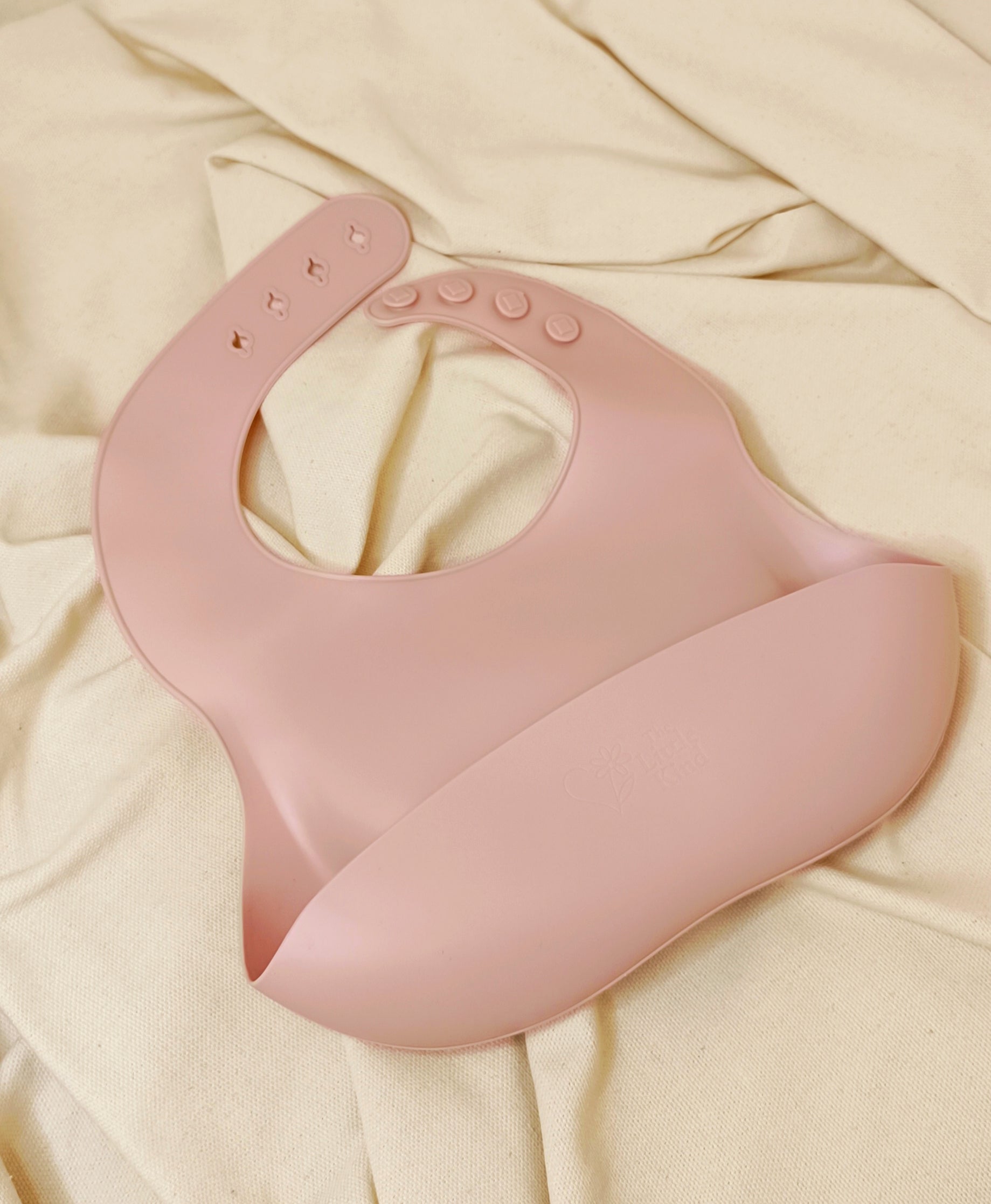 Pink silicone bib on a beige fabric background