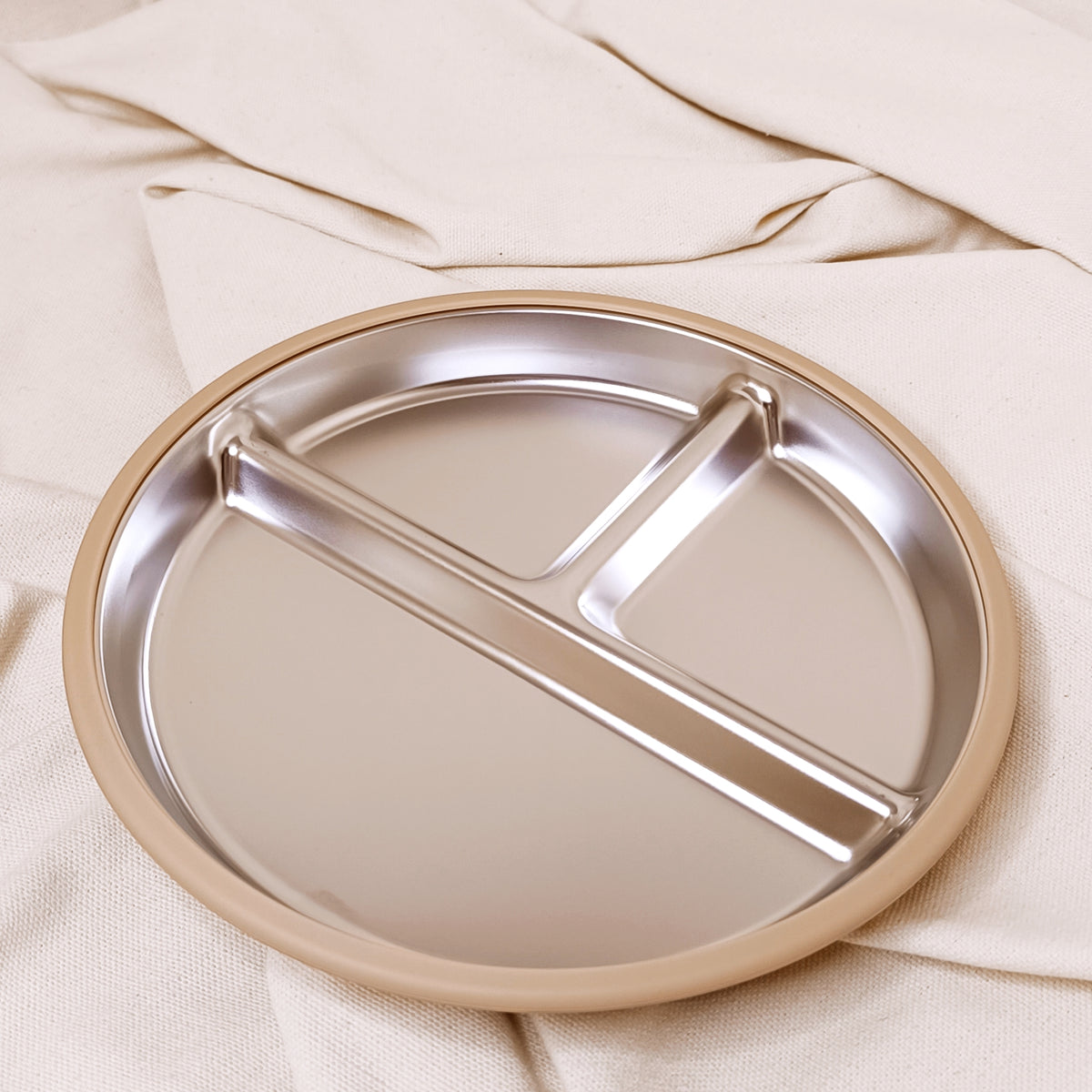 Stainless sreel plate with divided sections on a beige fabric background
