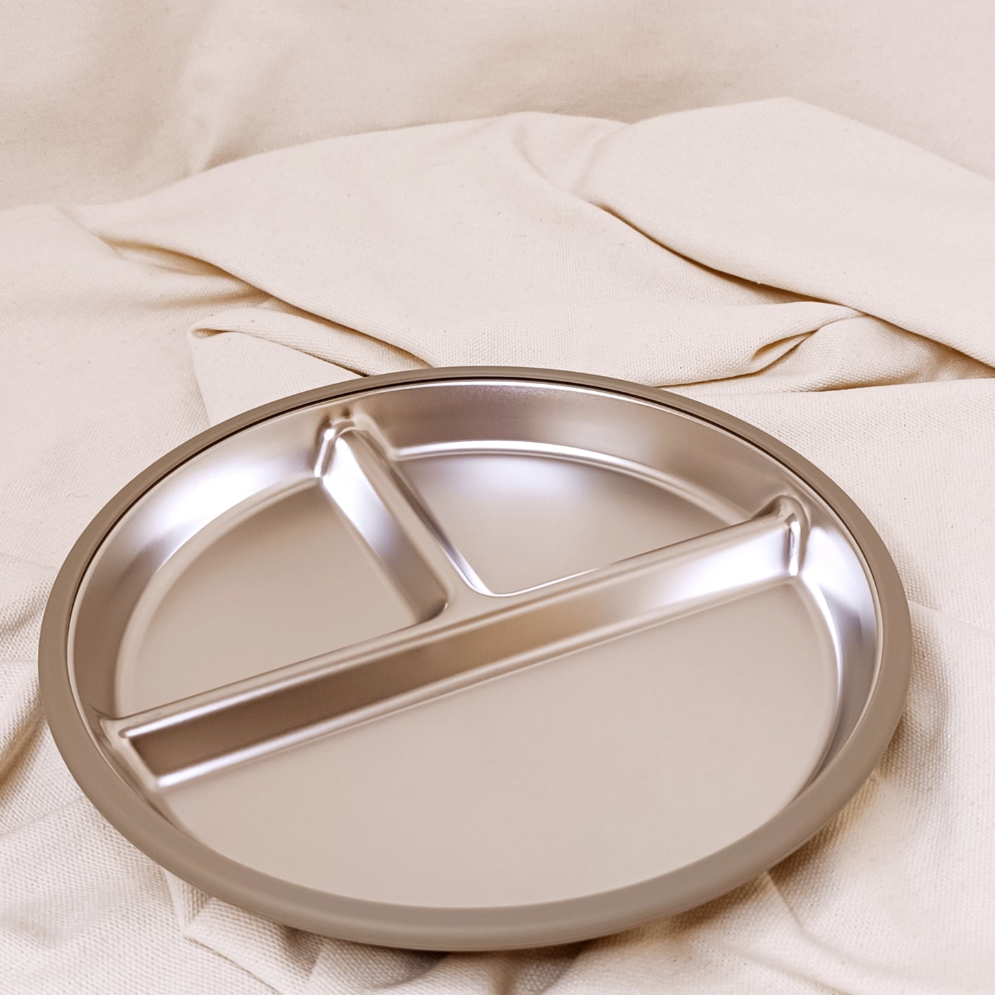 Round olive plate with three sections on a beige fabric background