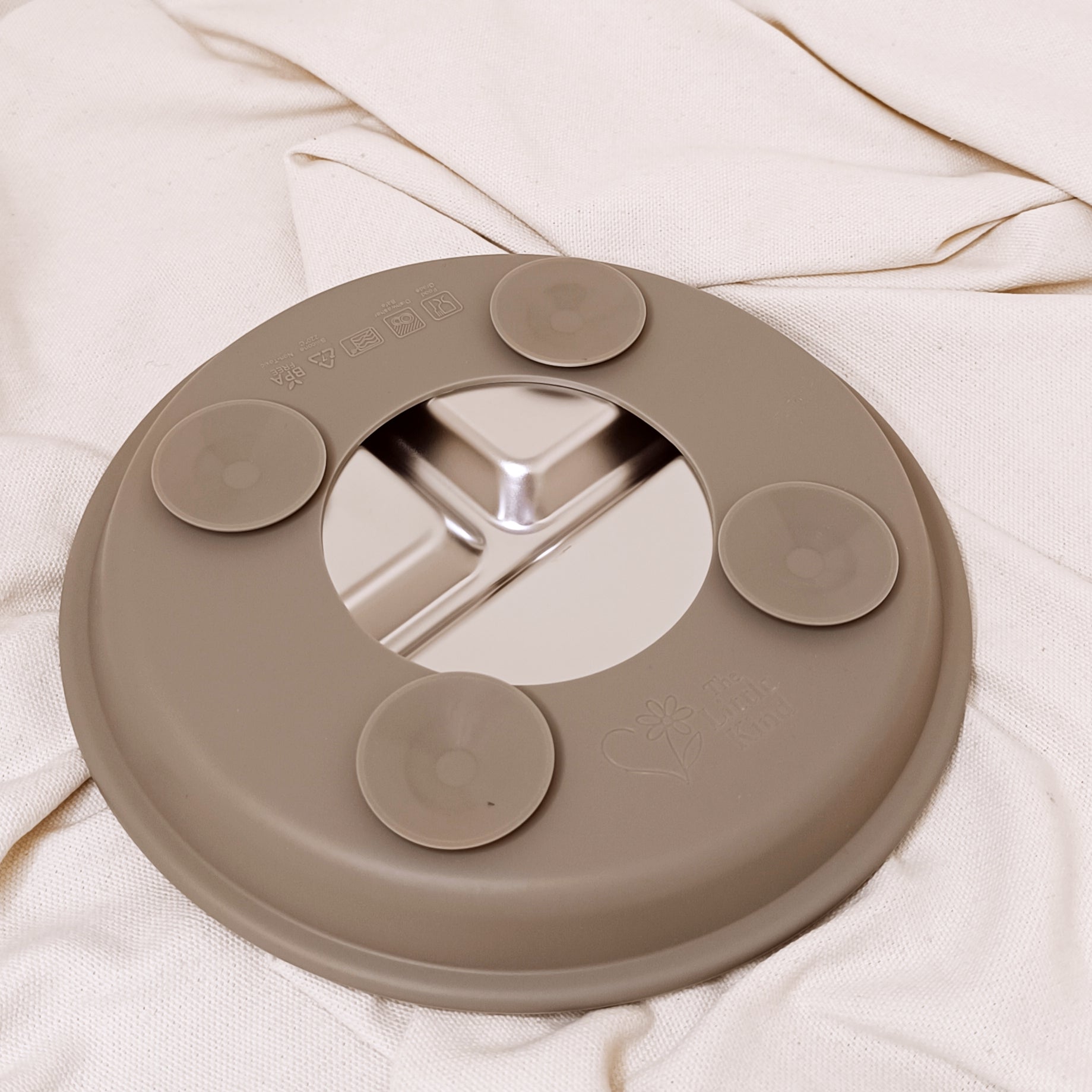 Round silicone suction plate in olive on a white fabric background