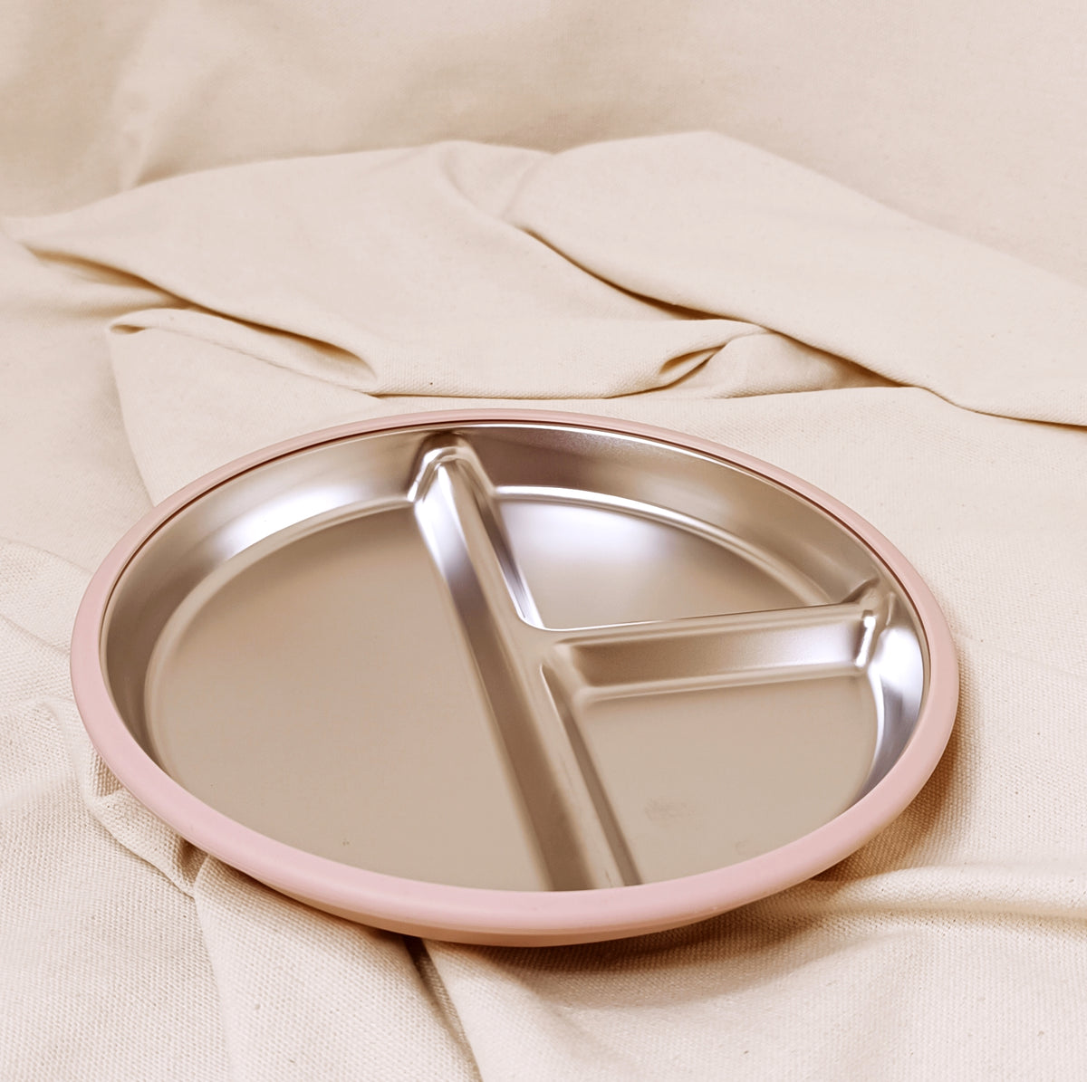 Divided plate with pink rim on a beige fabric background