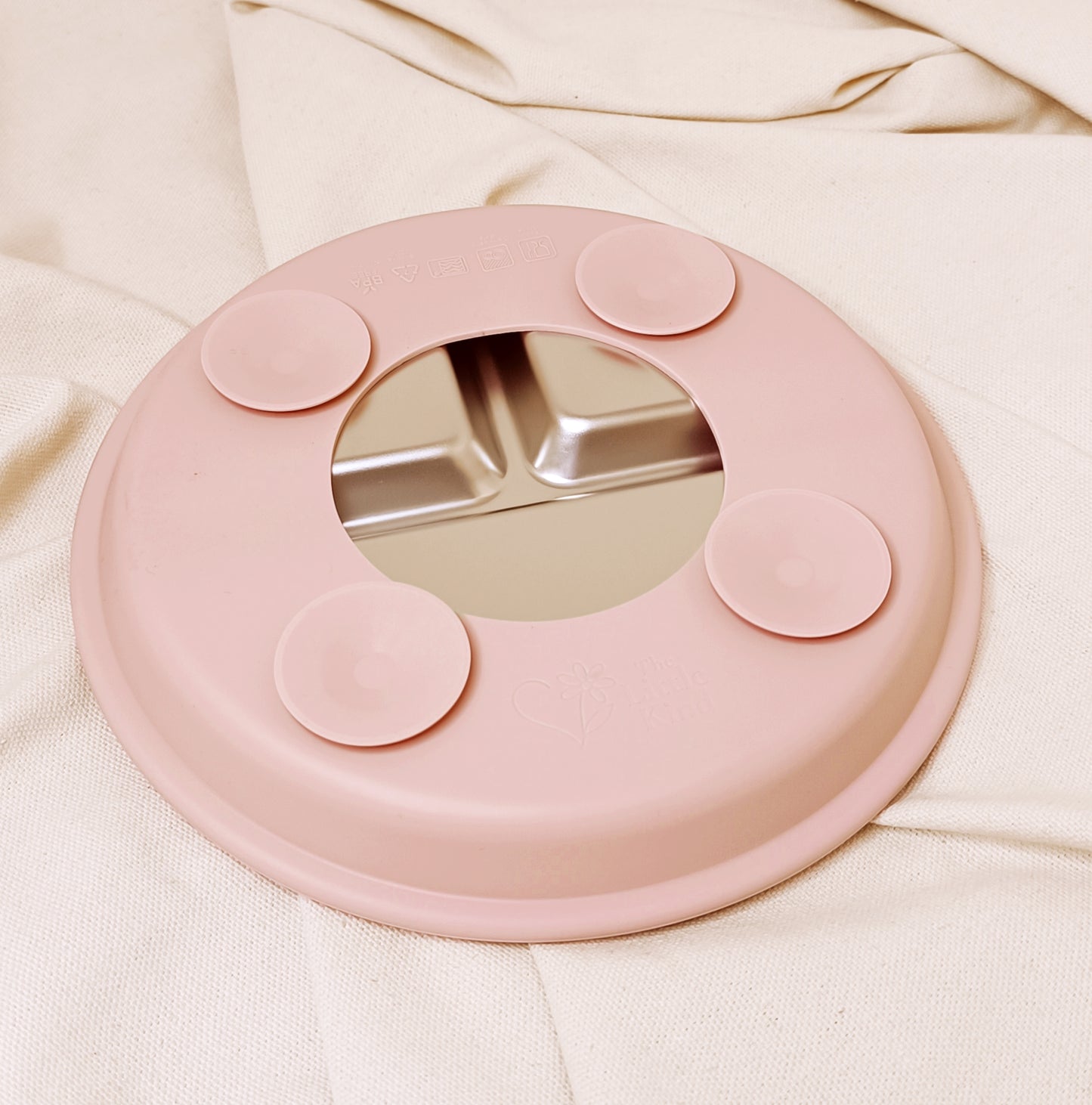 Pink silicone suction plate on a beige fabric background