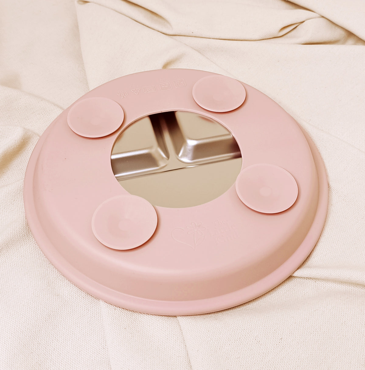 Pink silicone suction plate on a beige fabric background