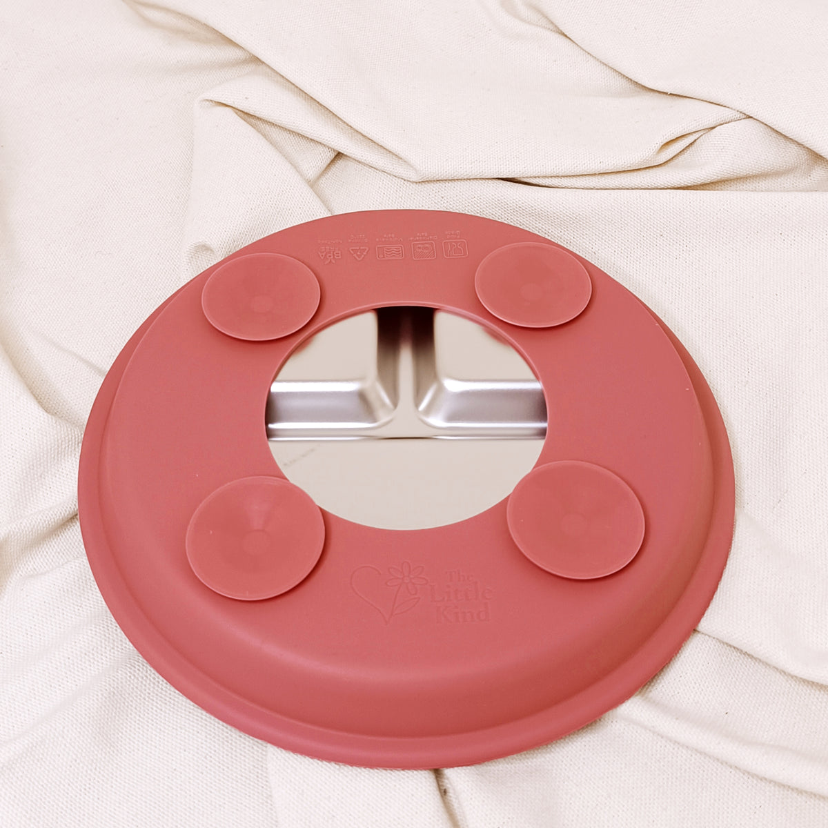 Pink silicone suction plate on a beige fabric background