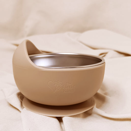 Beige bowl with a suction cup on a beige fabric background, featuring 'The Little Kind' logo.