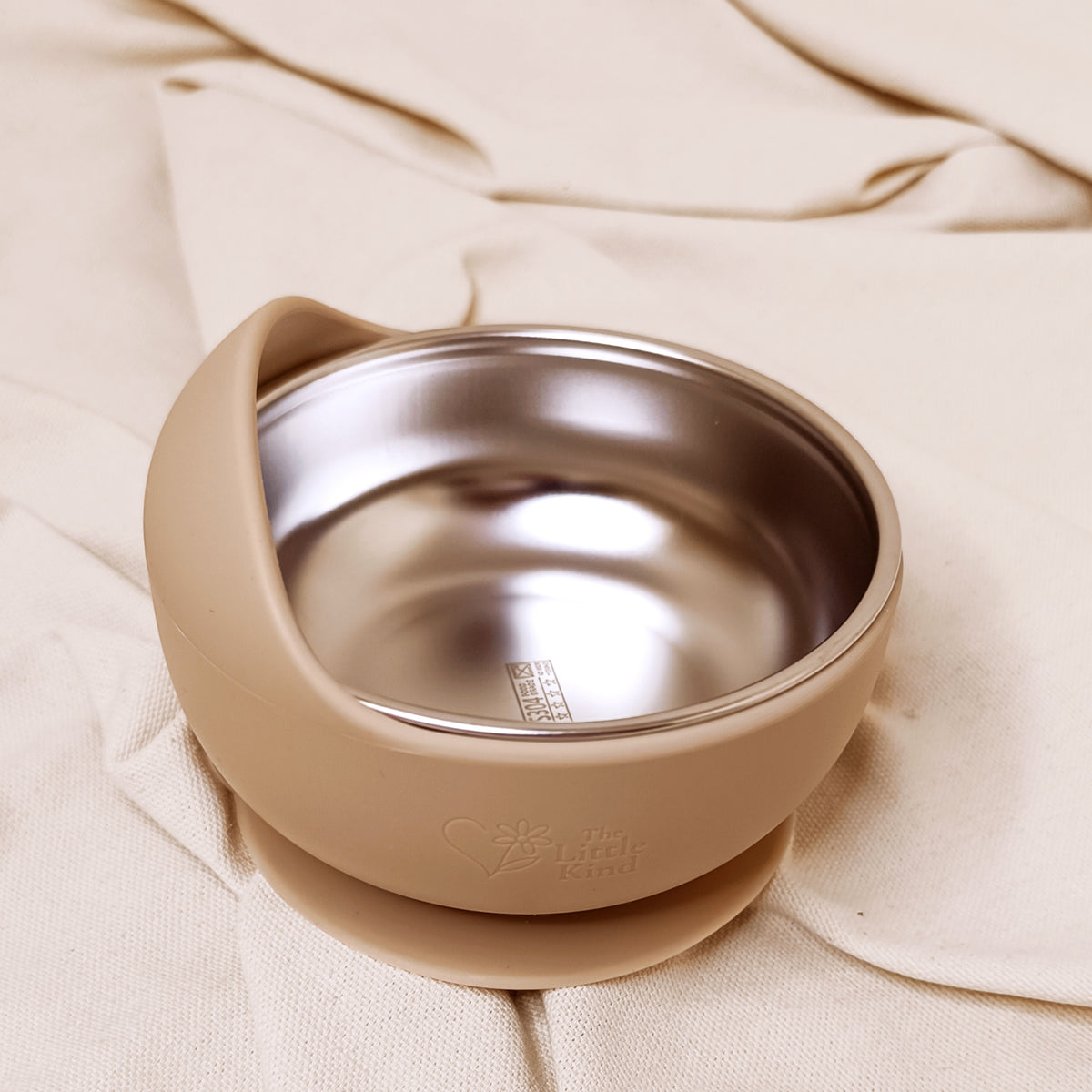 Beige bowl with a silicone base on a beige fabric background