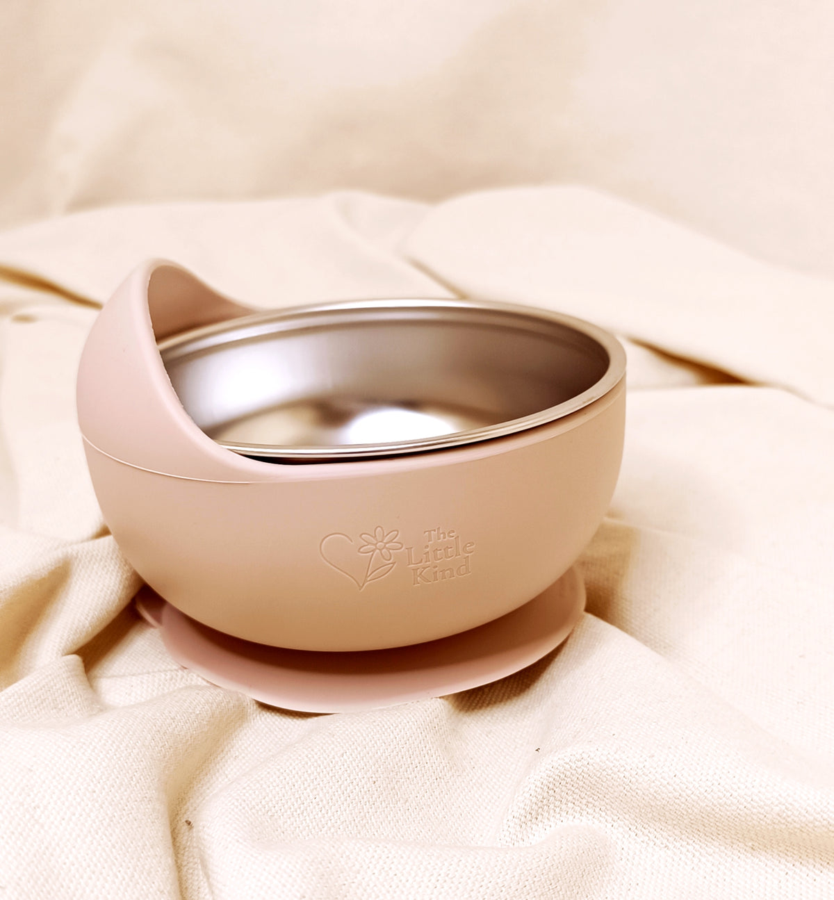 Pink silicone baby bowl on a beige fabric background